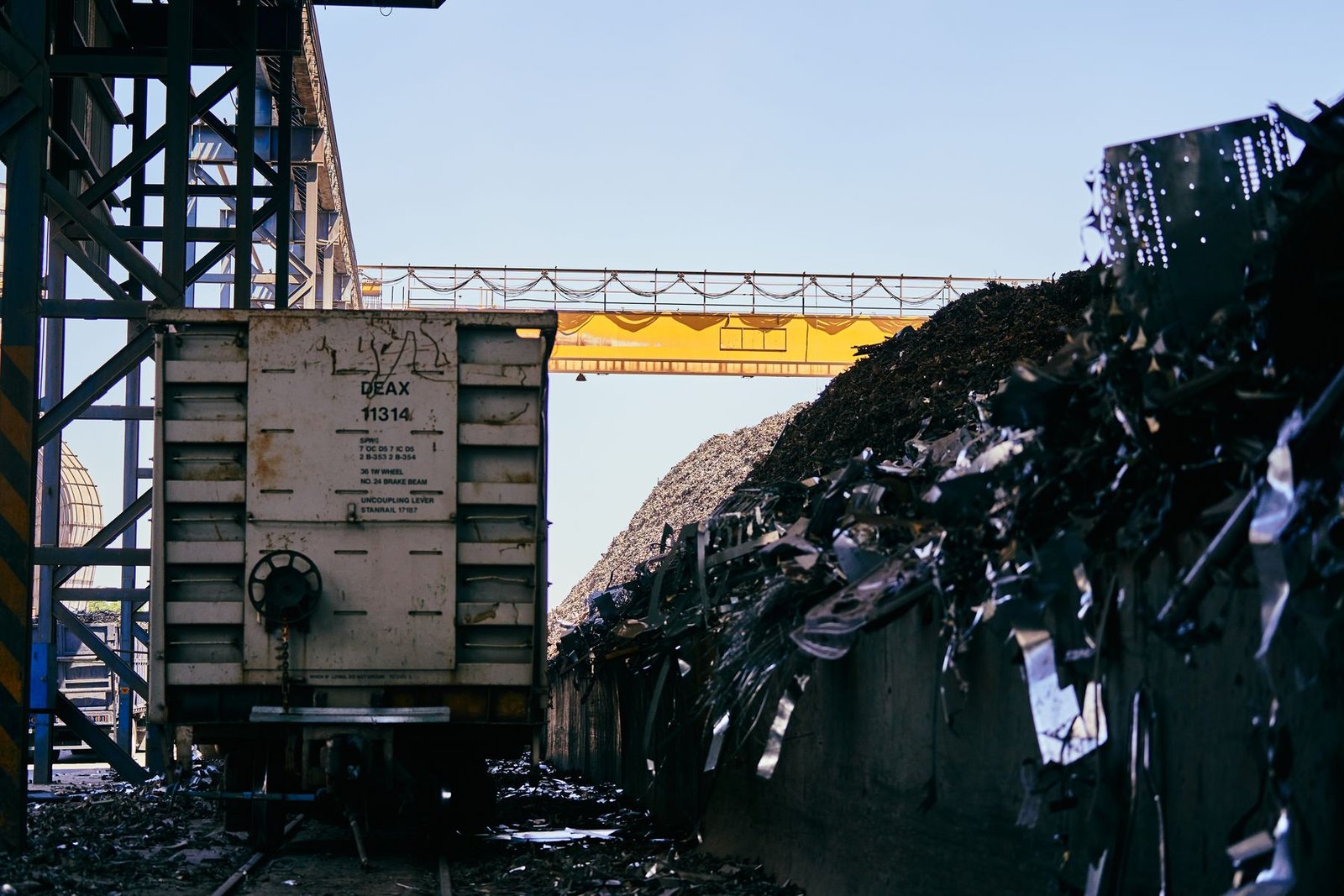 Endüstriyel hurda sahasında metal yığınları ve taşıma vagonu